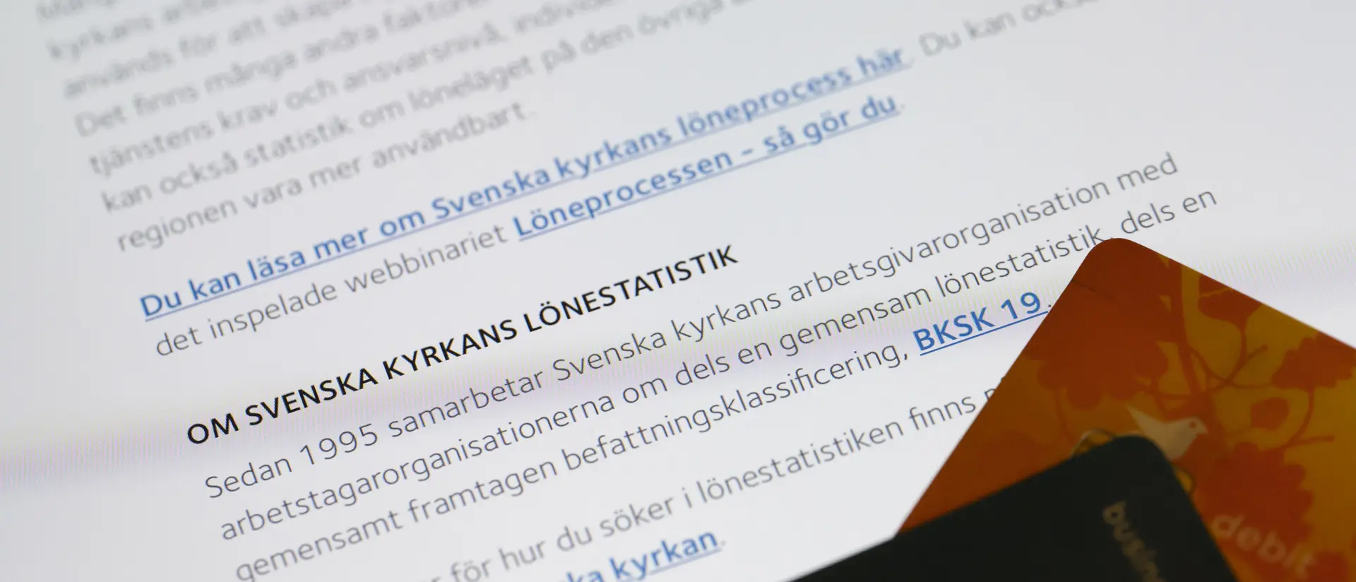 Papper om lönestatistik och två bankkort i förgrunden